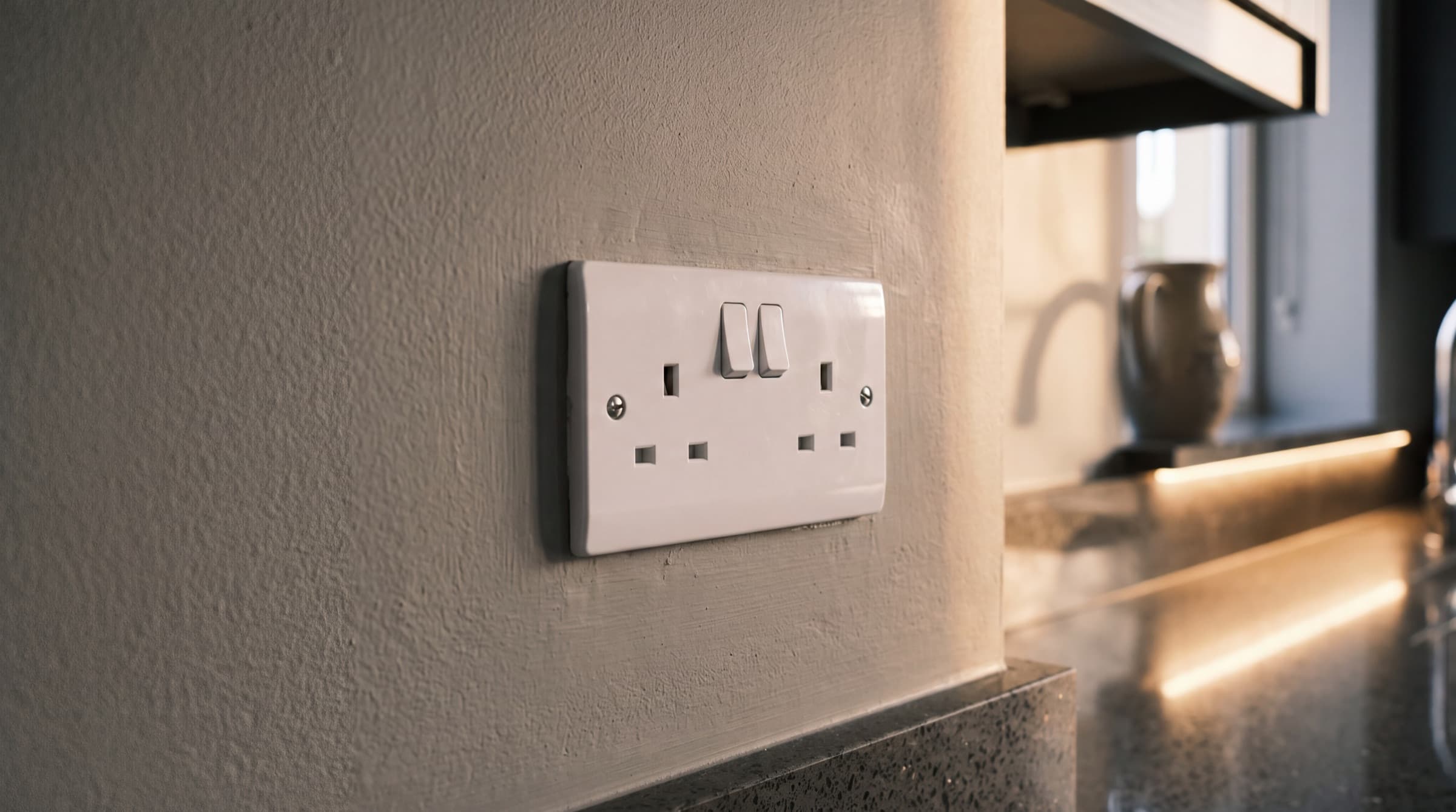 Close-up of a flush double socket installed in an Irish family home with warm under-cabinet LED lighting reflecting from a quartz worktop